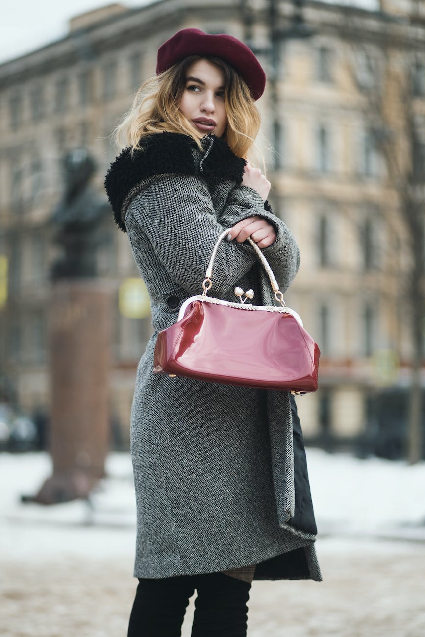 selective focus photography woman wearing gray coat standing near building